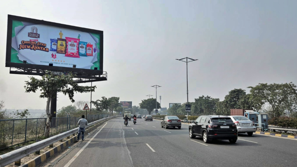 Digital billboard outdoor advertising displaying India Gate food product campaign on a highway gantry advertising structure.