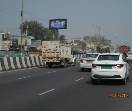 Busy highway in India with cars, taxis, and trucks, commercial buildings and an Indian cricket match billboard