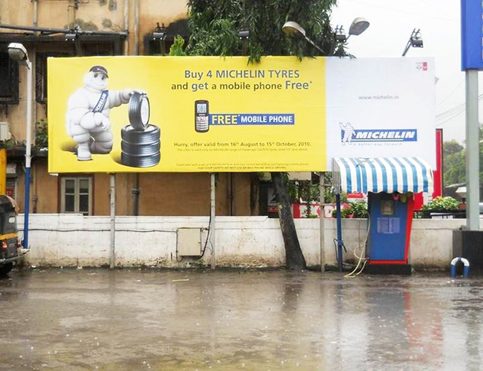 Michelin billboard ad: Buy 4 tyres, get a free mobile phone. Featuring Michelin Man and offer details.