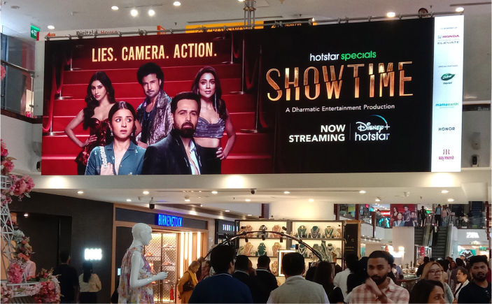 Large LED billboard mall advertising display above shopping mall corridor promoting entertainment campaign by ACME Advertising